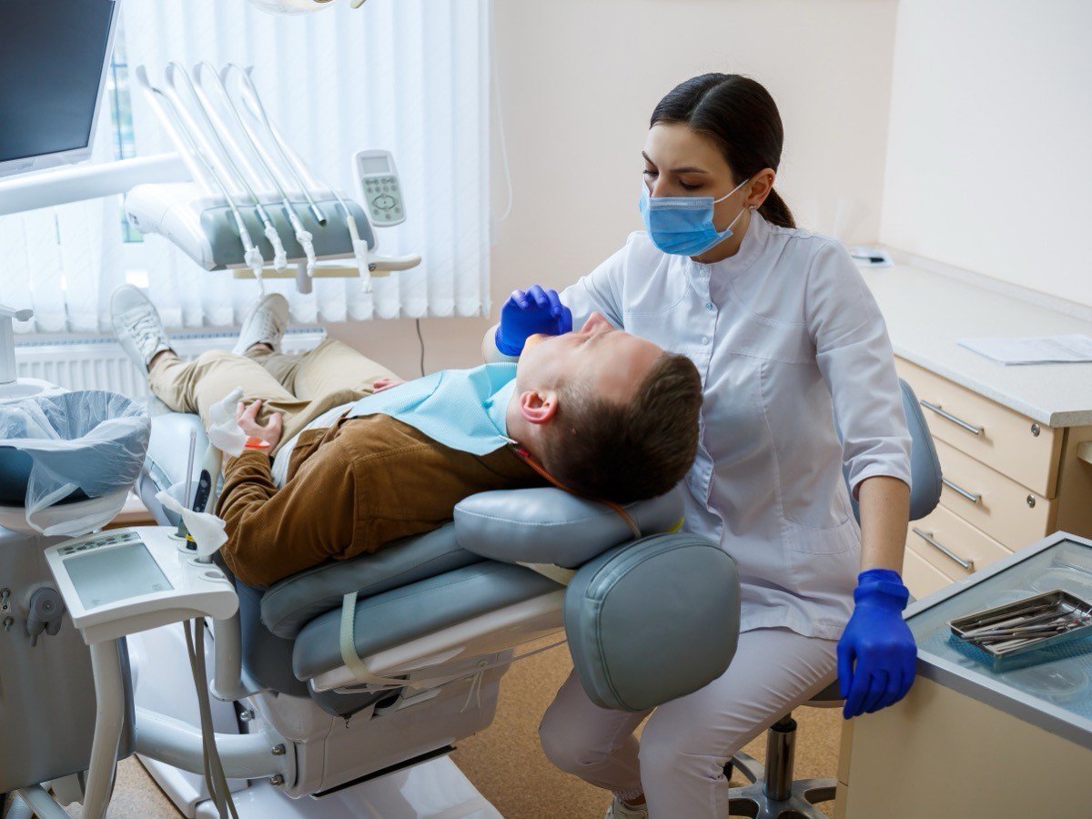 A dental surgical operatory in use — a clinician working chairside in a fully equipped treatment room